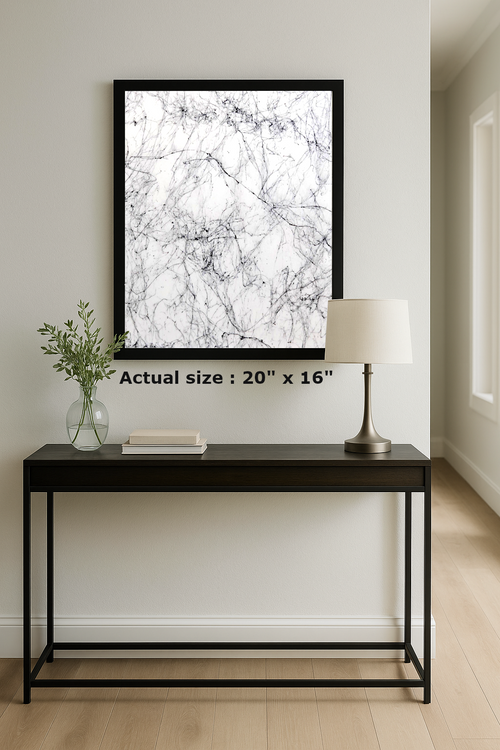 Framed abstract art on a wall above a black console table with a lamp and vase.